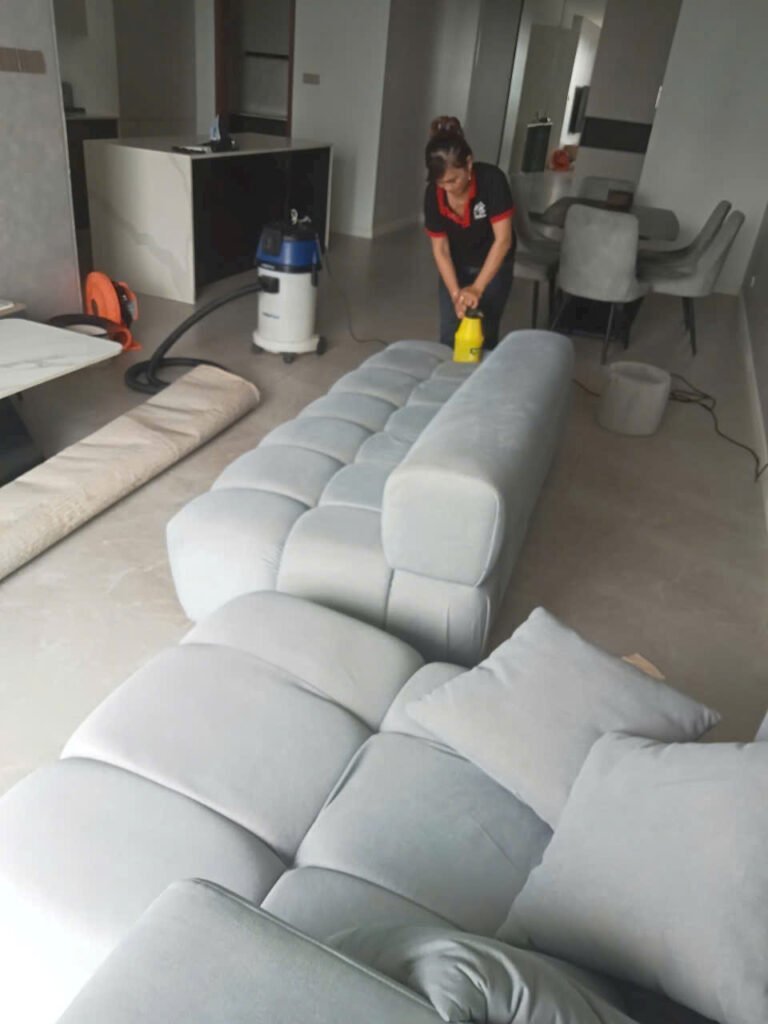 nhân viên hút bụi sofa vải trước khi giặt tại nhà